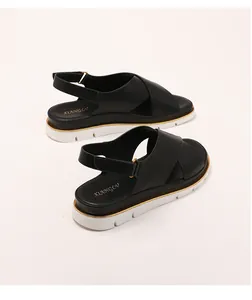 Detail of black platform sandals with leather cross straps and golden metal buckle