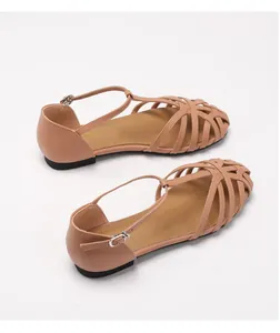 Detail of woven apricot flat sandals showing the hollow strap design and ankle buckle