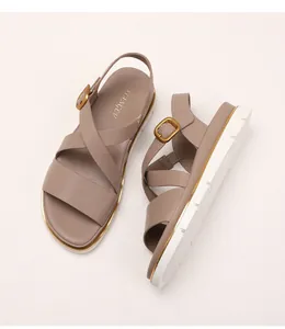 Detailed close-up of a wedge sandal with crisscross leather straps and golden metal buckles