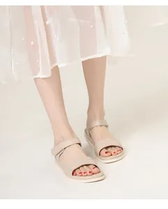 Close-up of beige leather sandals featuring adjustable velcro straps and non-slip rubber soles