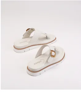 Close-up of cream flip-flop sandal featuring a gold buckle and thick non-slip sole
