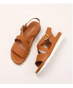 Close-up of brown leather wedge sandals featuring metal buckles and white serrated soles