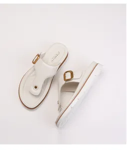 Close-up of beige platform flip-flops with wide T-straps and golden metal buckles