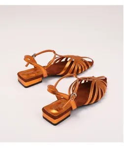Detail of orange metallic strappy sandals featuring a T-strap buckle and woven design