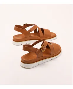 Close-up of brown leather wedge sandals with white serrated sole and metal buckle