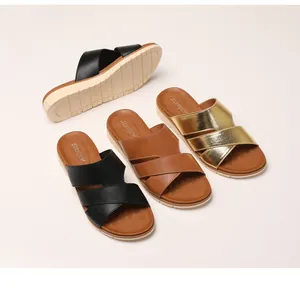 Close-up of thick platform sandals featuring textured cross straps in black brown and gold