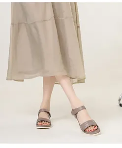 Detail of taupe leather sandals with velcro straps and soft non-slip soles on a model