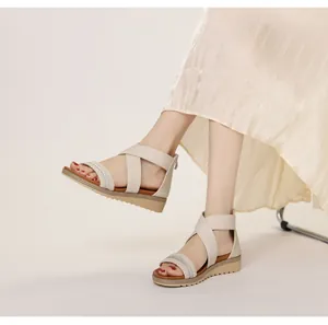 Detail of woven rhinestone straps on beige wedge sandals with cross-over design