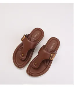 Detailed top view of brown leather flip-flops with golden buckles and white thick soles