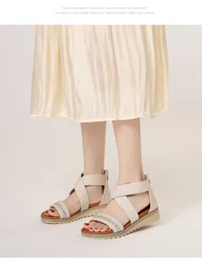 Detailed view of beige wedge sandals featuring rhinestone cross straps on model feet