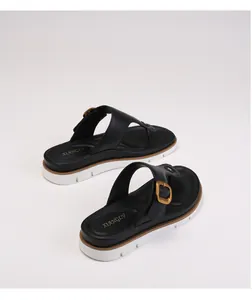 Detail view of platform flip flops featuring thick white sole and large gold buckle