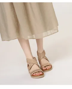 Close-up of rhinestone woven straps and cross design on women's wedge sandals
