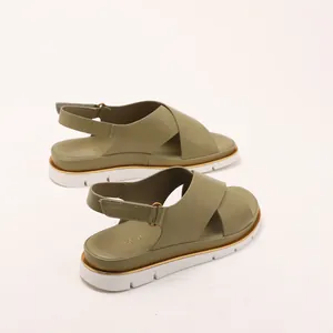 Olive green platform sandals with crisscross straps and gold trim on sawtooth sole