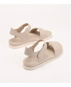 Close-up of beige flat sandals with adjustable velcro straps and breathable footbed