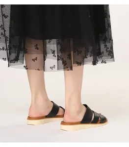 Detail of black cross-strap platform slide sandals with thick sole on model