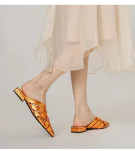 Detail of orange woven pointed-toe mule shoes featuring metallic texture and block heel