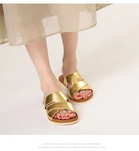 Close-up of golden metallic cross-strap slide sandals with comfortable white sole