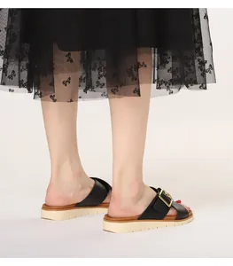 Detail of black platform sandals featuring a large golden metal buckle on cross strap
