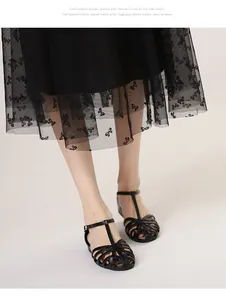 Close-up of black woven T-strap sandals with matte finish and metal buckle closure