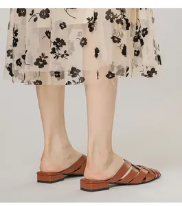 Detailed side view of brown woven leather pointed-toe mule heels with summer floral skirt