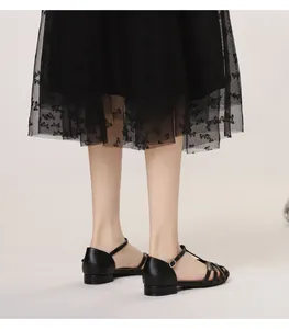 Detail view of black woven gladiator sandals with T-strap and buckle on mesh skirt model