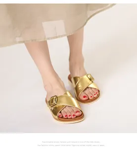 Close-up of golden metallic crossover straps with square buckle on thick-soled beach sandals