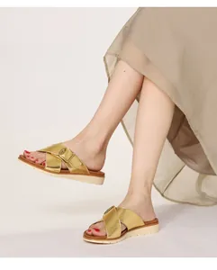 Detailed side view of golden platform sandals with crisscross straps and metal buckles