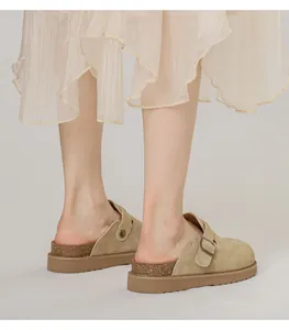 Rückansicht von khakifarbenen Wildleder-Clogs an Model mit Schnalle und dicker Gummisohle