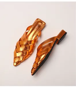 Macro shot of bright orange metallic woven texture on pointed toe mule shoes