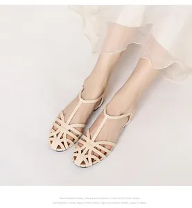 Top view of beige woven flat sandals with T-strap design on a white pleated skirt model