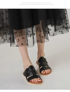 Détail de la semelle compensée beige et des lanières croisées en cuir noir de la sandale