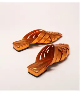 Detailed top view of orange gold woven leather pointed toe mules with metallic finish