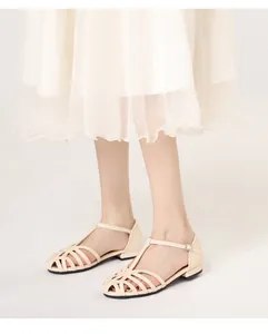 Detail of cream woven cage sandals featuring T-strap buckles and hollow vintage design