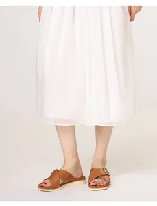 Detail of brown leather platform slides with cross-strap and gold buckle on model