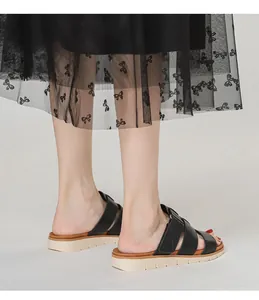 Gros plan de sandales compensées en cuir noir portées avec une jupe en tulle