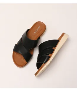 Detail view of women's thick sole slippers with black cross straps and branded insoles