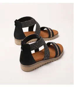 Detail of black wedge sandals featuring rhinestone woven straps and rear zipper closure