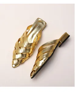 Close-up of golden woven pointed-toe mule featuring metallic texture and low block heel