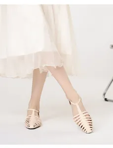 Detail of cream woven caged Roman sandals with metal buckle styled with a white skirt