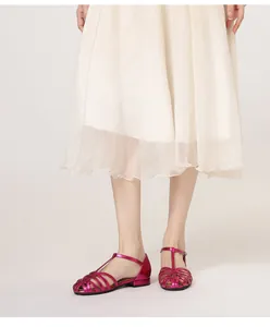 Detail of rose pink woven sandals featuring cage-style cutouts and T-bar buckles