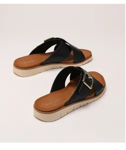 Detail view of platform slide sandals featuring black crisscross straps and gold buckles