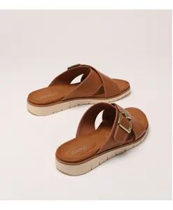 Detail of cross-strap platform sandals with golden metal buckles and textured brown leather