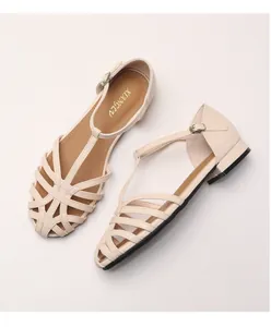 Close-up of woven closed-toe sandals in creamy white with T-strap buckle and low heel