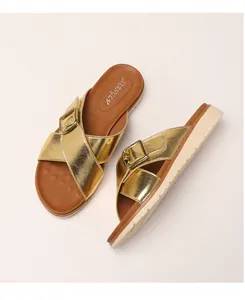 Close-up of golden metallic crisscross straps with large buckle and thick platform sole