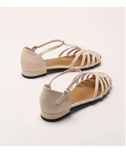 Detailed view of beige woven leather sandals with T-strap and metal buckle closure