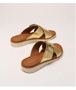 Close-up of golden platform sandals with crisscross straps and metal buckle detailing