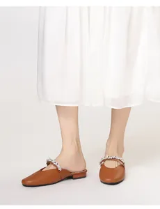 Close-up of brown pointed-toe mule shoe with a sparkling rhinestone strap decoration