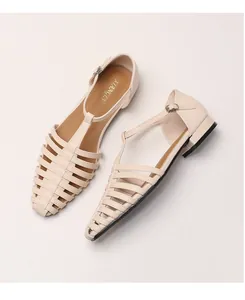 Detail of beige woven fisherman sandals with T-strap buckle and low square heel