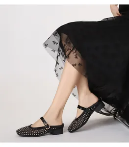 Détail d'une mule en maille avec clous argentés et boucle dorée sur tige noire