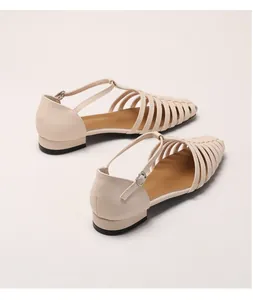 Detail of cream woven fisherman sandals featuring T-strap design and silver metal buckle
